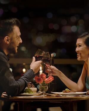 couple clinking wine glasses over dinner