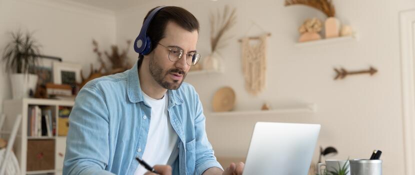 man on laptop taking notes at home